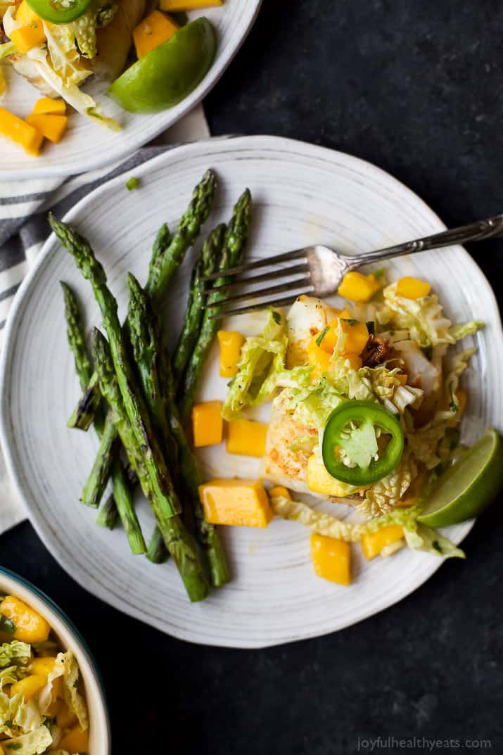 Top view of Grilled White Fish topped with Mango Jalapeno Coleslaw next to asparagus on a plate