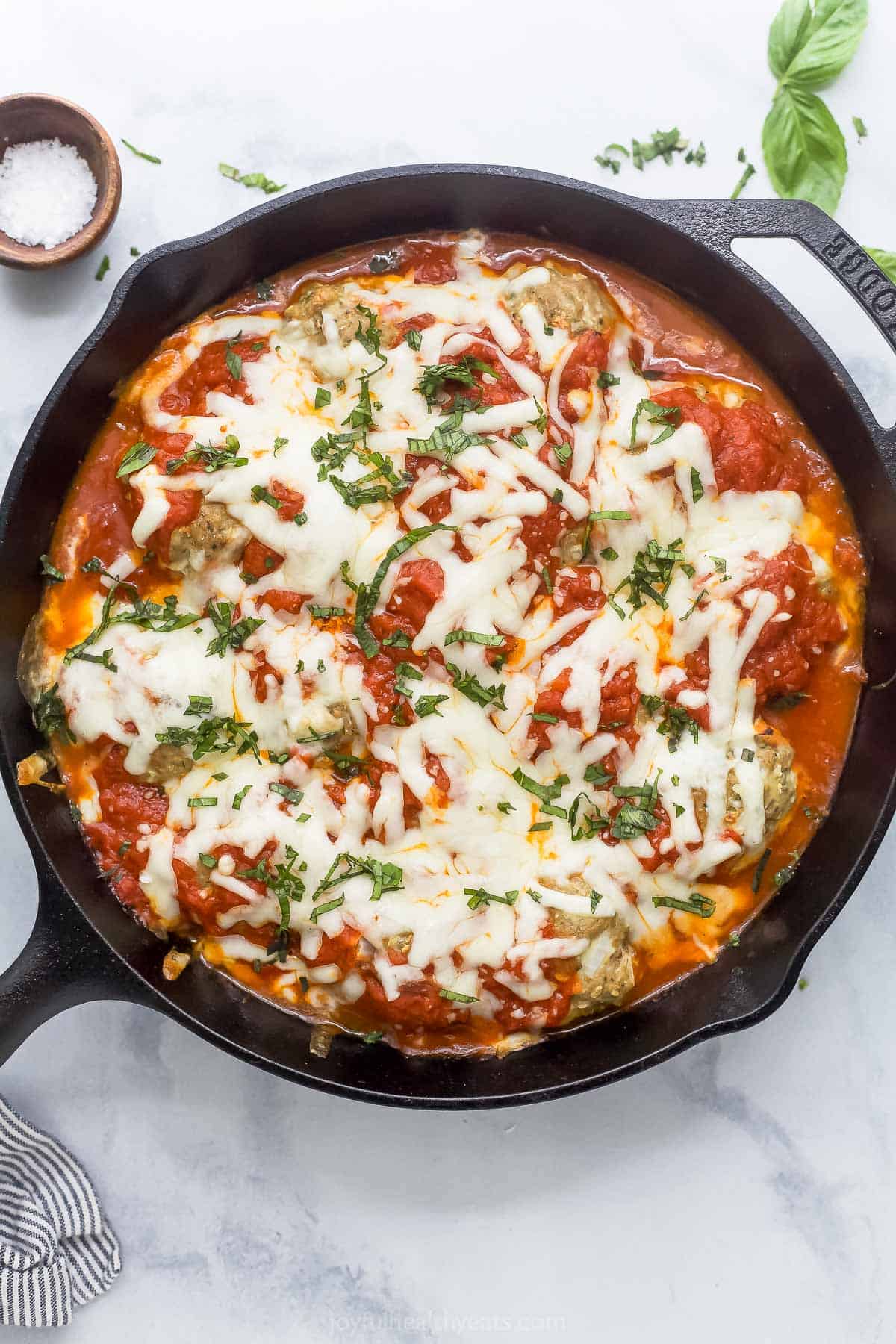These Baked Turkey Meatballs are cooked in marinara to keep them flavorful and moist, and they’re also loaded with cheese. Done in 30 minutes! Overhead view of baked turkey meatballs in cast iron skillet