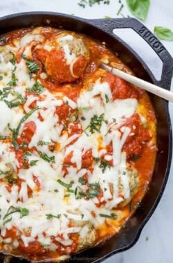 Overhead view of baked turkey meatballs in cast iron skillet with marinara and mozzarella