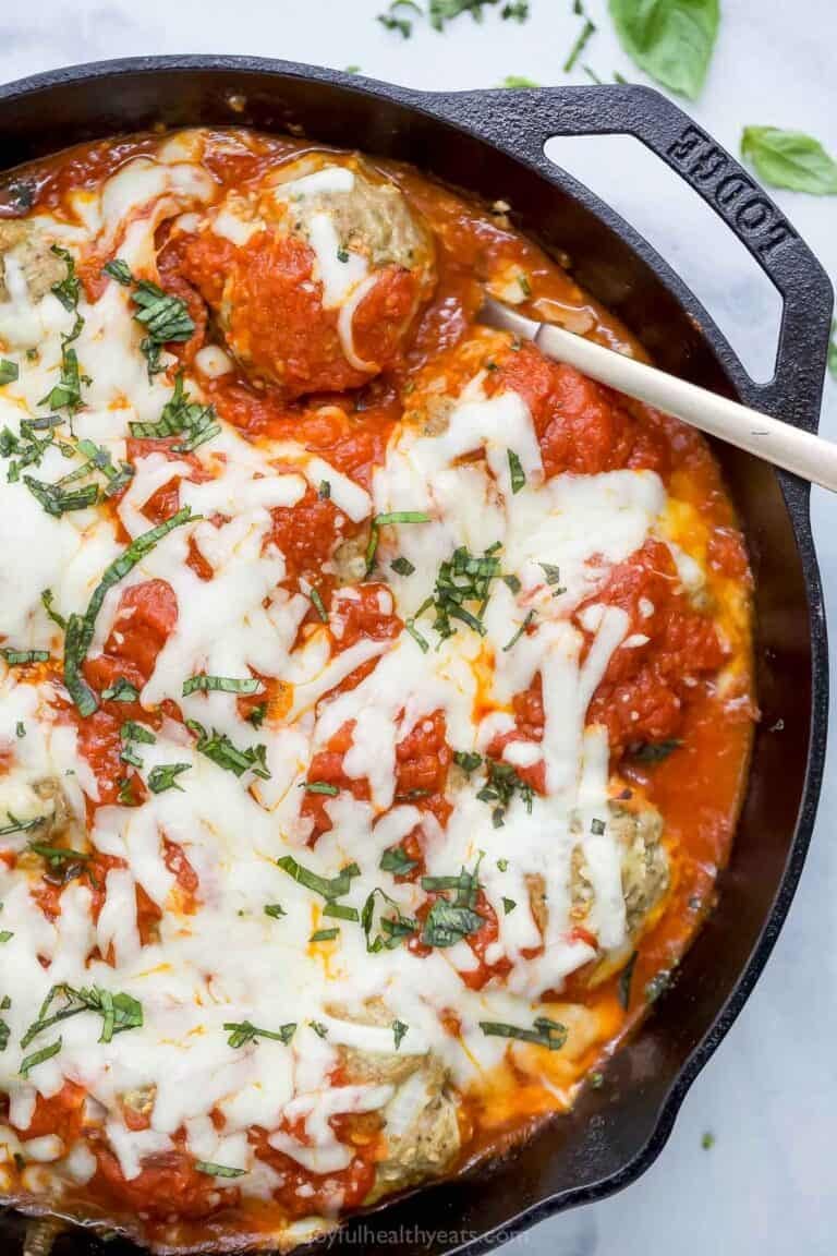 Overhead view of baked turkey meatballs in cast iron skillet with marinara and mozzarella