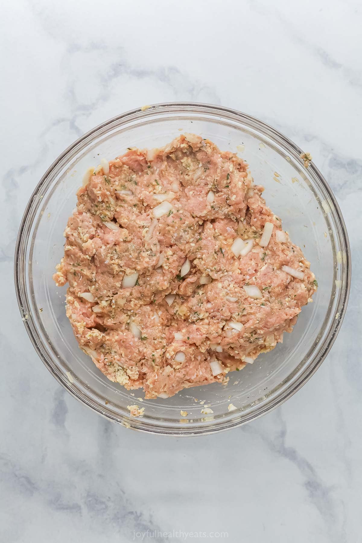 These Baked Turkey Meatballs are cooked in marinara to keep them flavorful and moist, and they’re also loaded with cheese. Done in 30 minutes! Turkey meatball mixture in glass mixing bowl