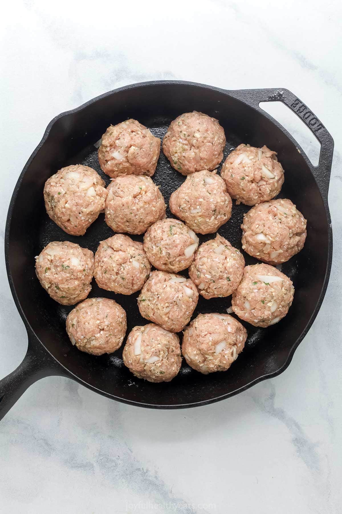 These Baked Turkey Meatballs are cooked in marinara to keep them flavorful and moist, and they’re also loaded with cheese. Done in 30 minutes! Overhead view of turkey meatballs in cast iron skillet before cooking