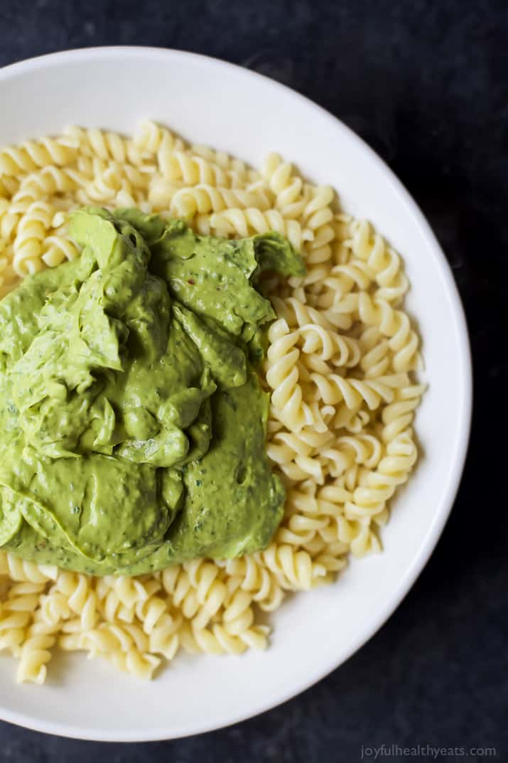 Top view of rotini pasta topped with creamy avocado sauce in a bowl