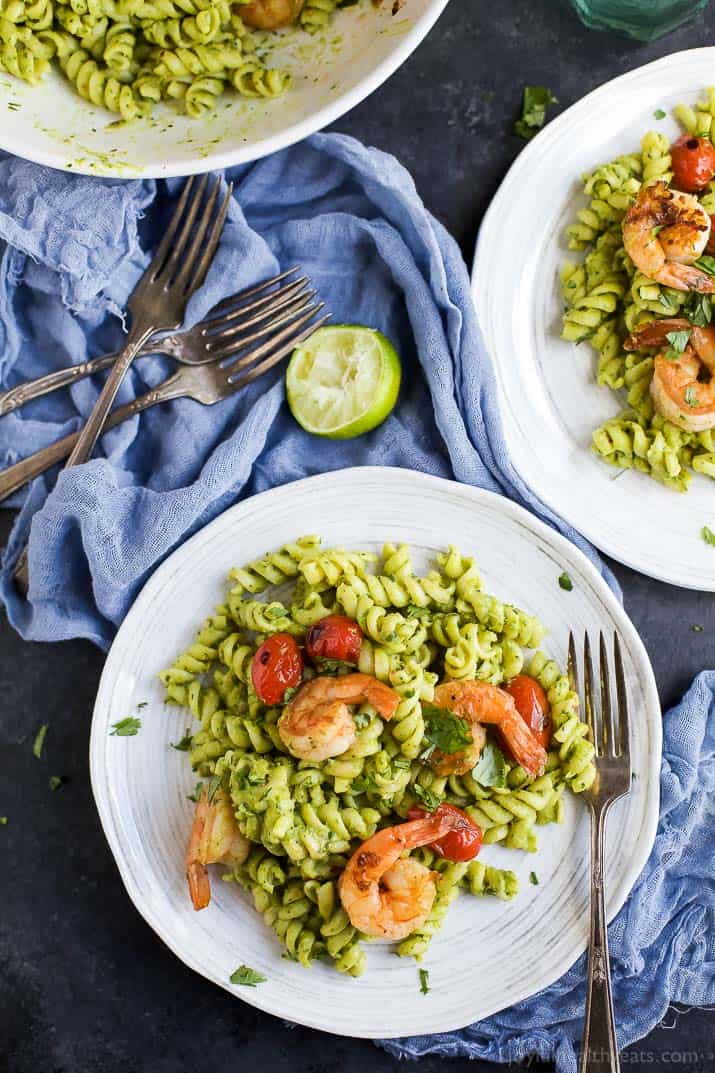 Overhead view of plates of Chimichurri Avocado Pasta with Pan Seared Shrimp and grape tomatoes