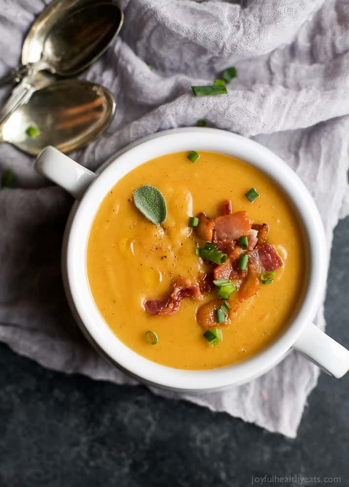 Top view of a crock of Creamy Bacon Roasted Butternut Squash Soup garnished with crumbled bacon and scallions