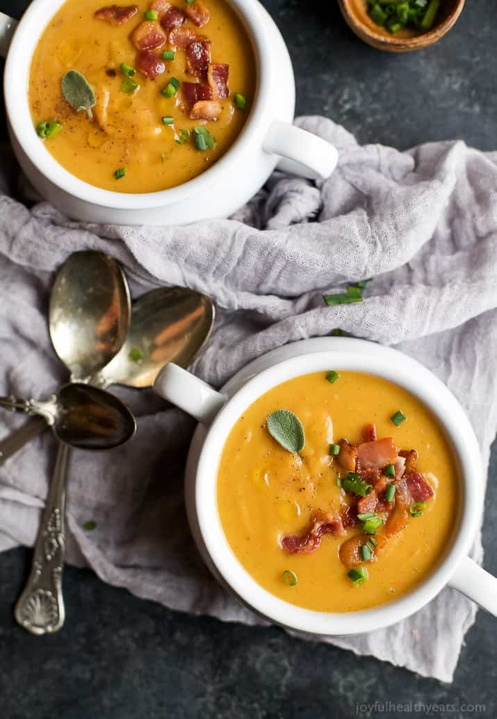 Top view of two crocks of Creamy Bacon Roasted Butternut Squash Soup garnished with crumbled bacon and scallions