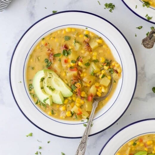 a bowl filled with easy crock pot potato corn chowder and topped with avocado