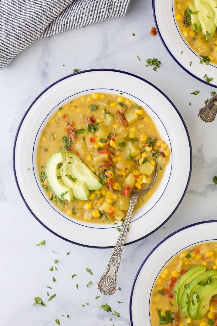 a bowl filled with easy crock pot potato corn chowder and topped with avocado