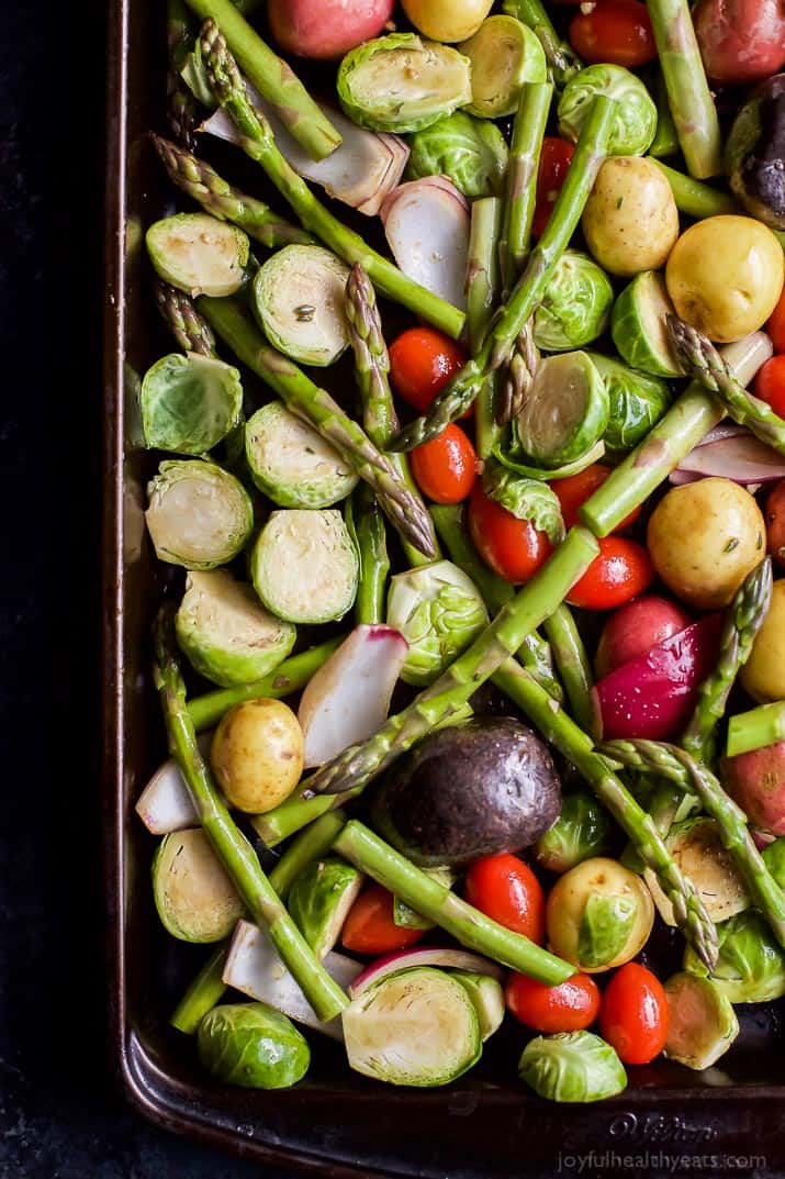 Potatoes, asparagus, and brussels sprouts laid out on a baking sheet