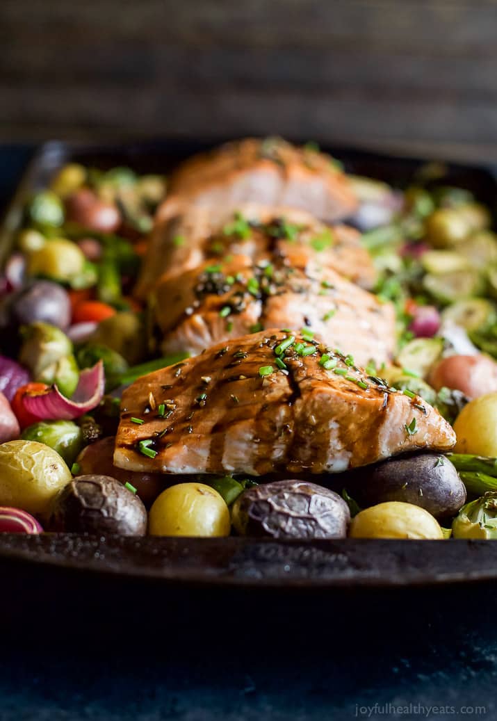 Salmon on a bed of potatoes, asparagus, and brussels sprout on a baking pan