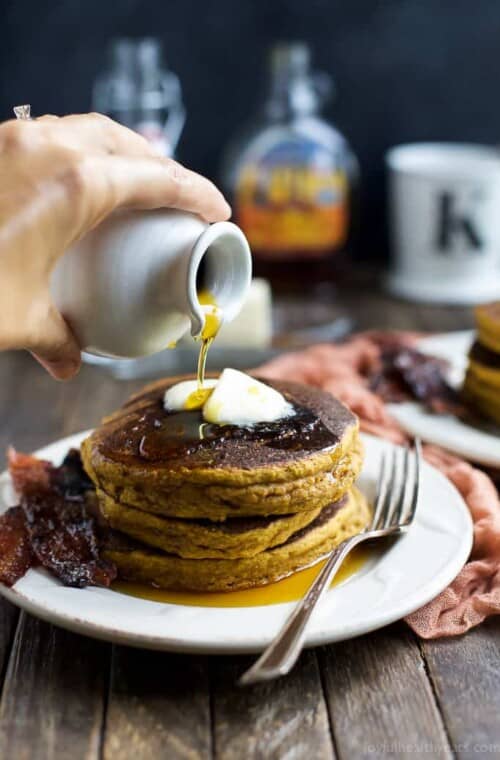 Pumpkin pancakes topped with two pats of butter and a drizzle of pure maple syrup