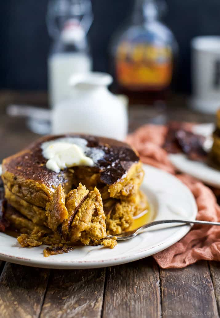 A stack of three whole wheat pumpkin pancakes with a fork digging into them