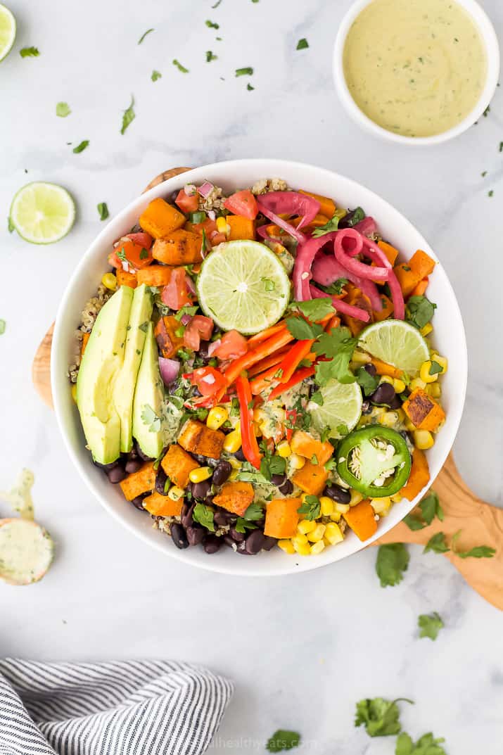 a bowl filled with easy sweet potato black bean quinoa topped with cilantro lime crema