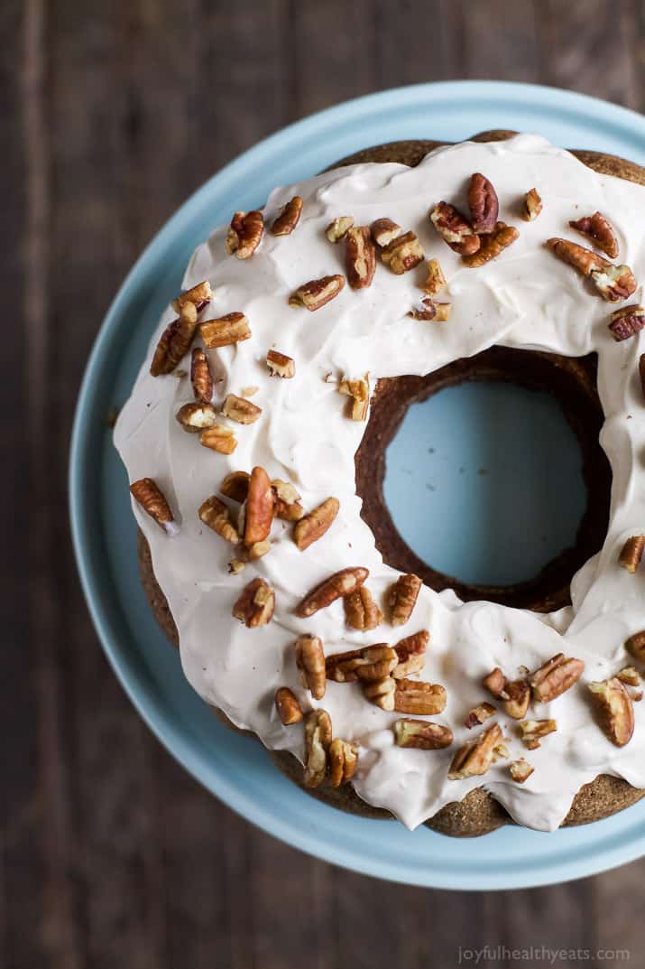 The top view of a frosted bundt cake with coarsely chopped pecans on top