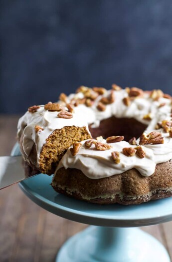 A metal spatula removing a piece of pumpkin bundt cake from a blue cake stand