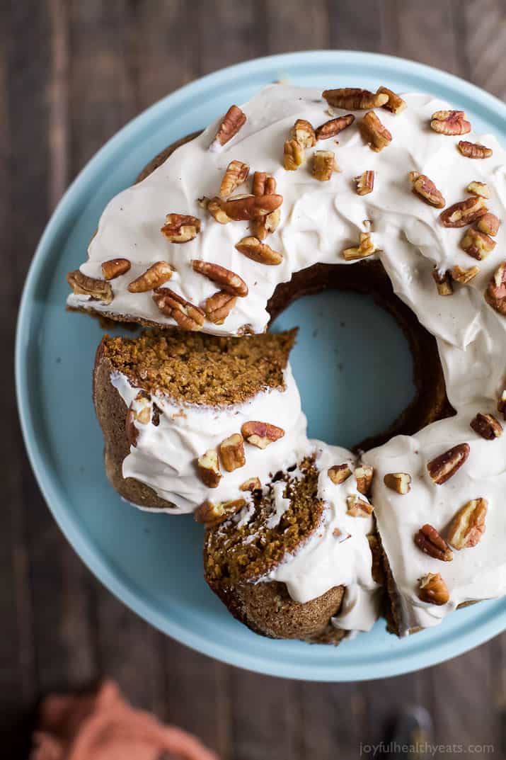 An overhead shot of a frosted pumpkin bundt cake with two slices cut out