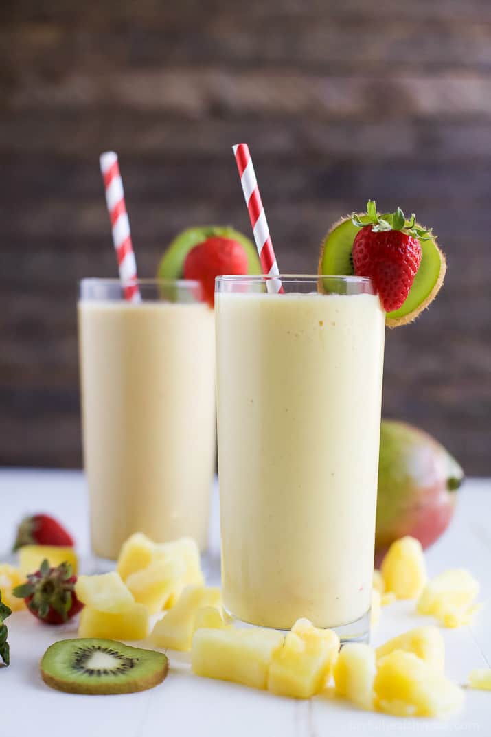 two smoothies that are pale yellow with a strawberry and kiwi garnish