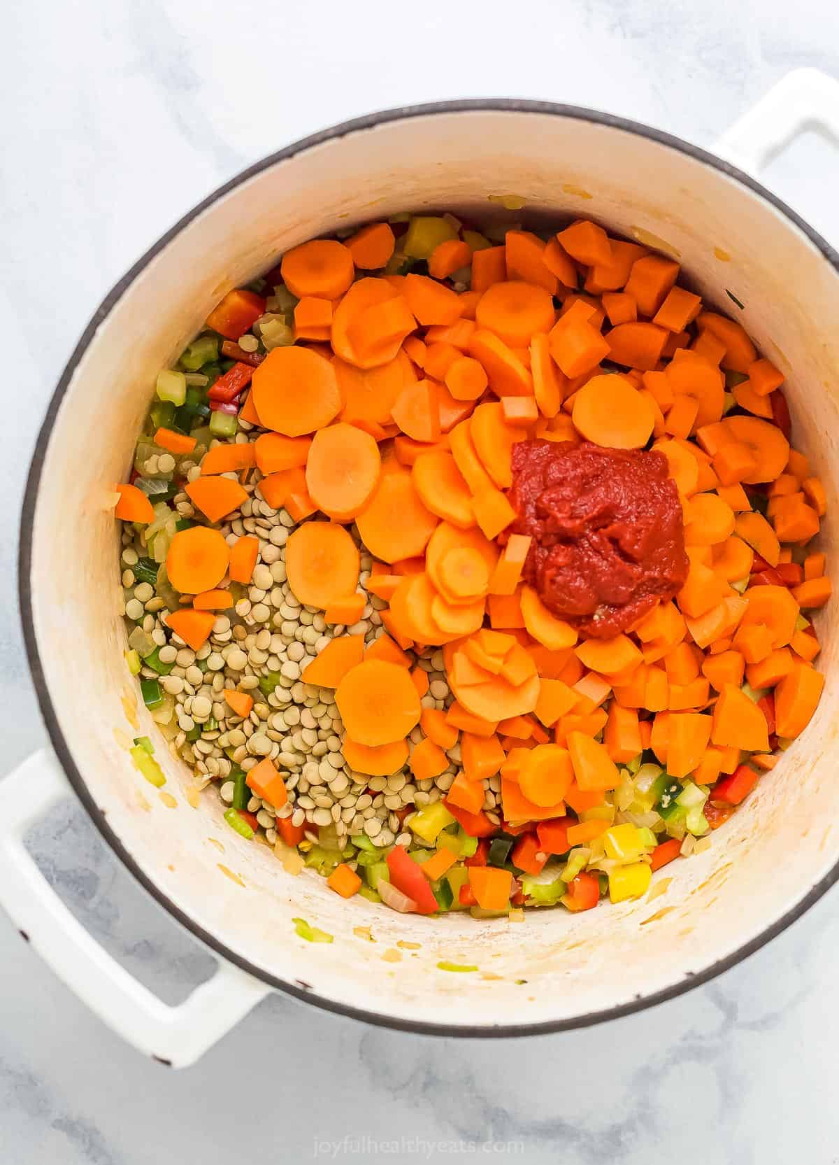 Carrots, tomato paste. and lentils in a dutch oven.