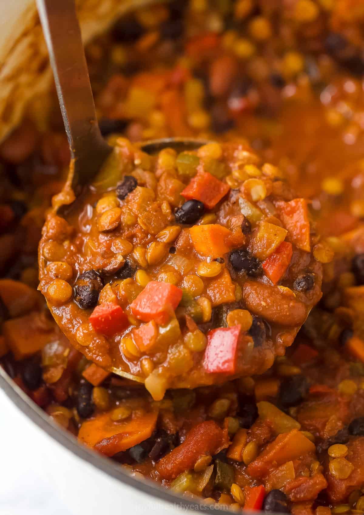 Ladle scooping lentil chili.