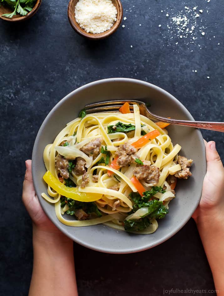 Top view of a bowl of Creamy Kale Pepper & Sausage Pasta with a fork