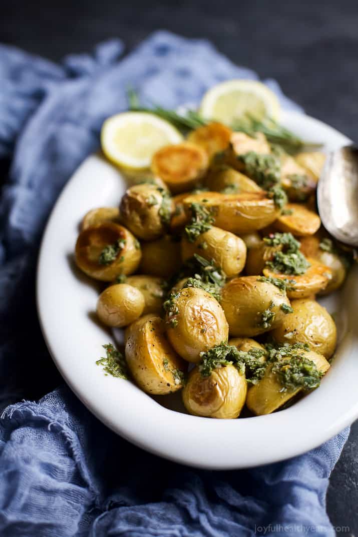 Crispy Oven Roasted Potatoes in a serving bowl with fresh herbs