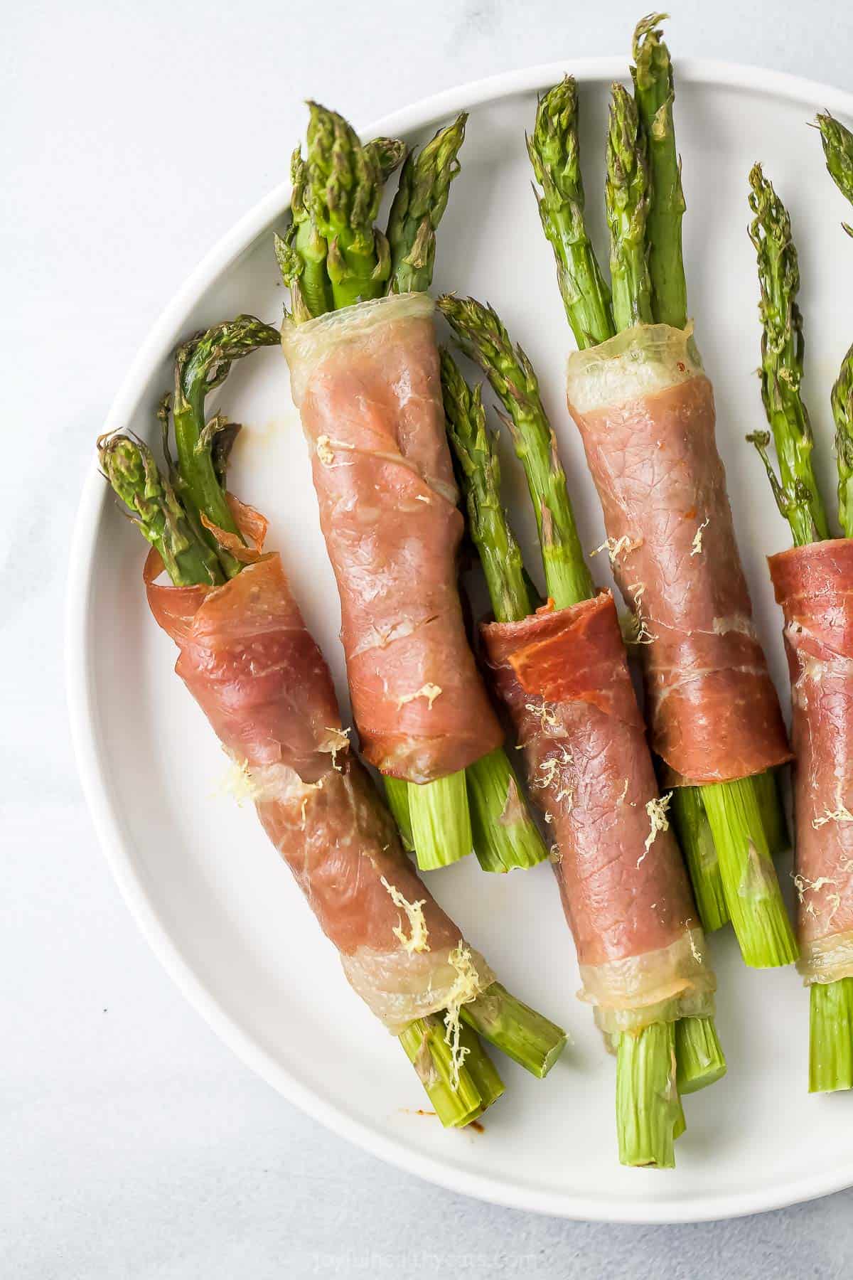 A close-up shot of prosciutto asparagus wraps on a round serving platter
