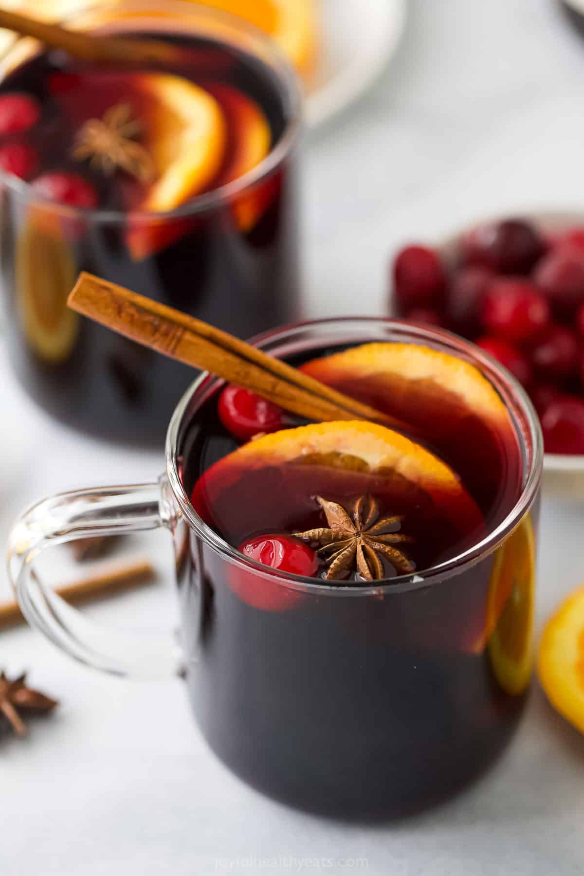 Gl، of mulled wine recipe with orange slices and a cinnamon stick. 
