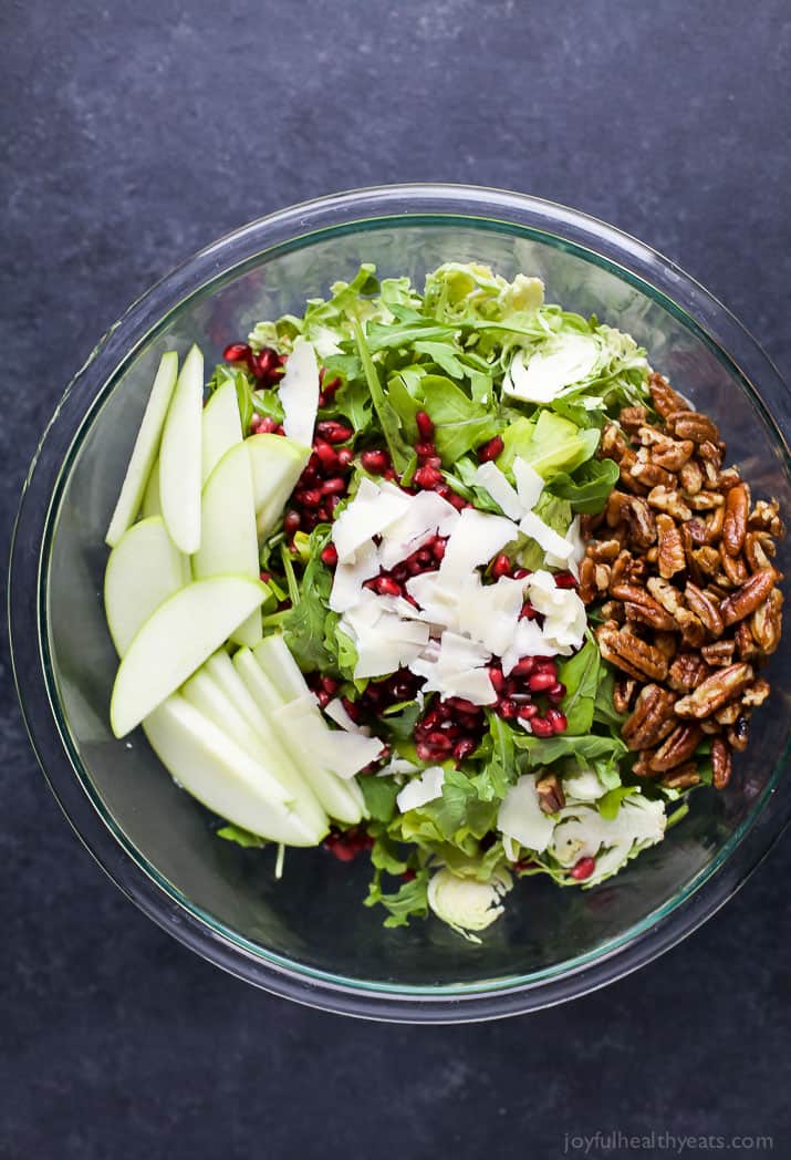 Shaved Brussel Sprout Salad filled with apples, pomegranate, candied pecans, and white cheddar cheese then tossed with a light Lemon Vinaigrette. This Brussel Sprout Salad is the perfect side dish for the holidays! | joyfulhealthyeats.com #glutenfree