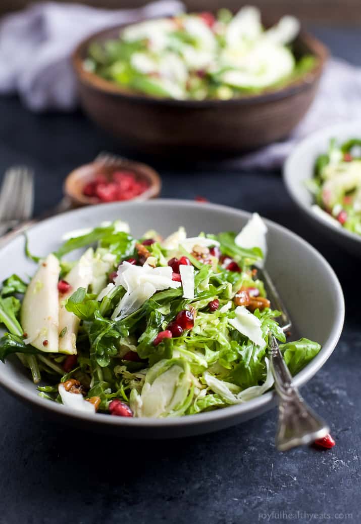 Shaved Brussel Sprout Salad filled with apples, pomegranate, candied pecans, and white cheddar cheese then tossed with a light Lemon Vinaigrette. This Brussel Sprout Salad is the perfect side dish for the holidays! | joyfulhealthyeats.com #glutenfree