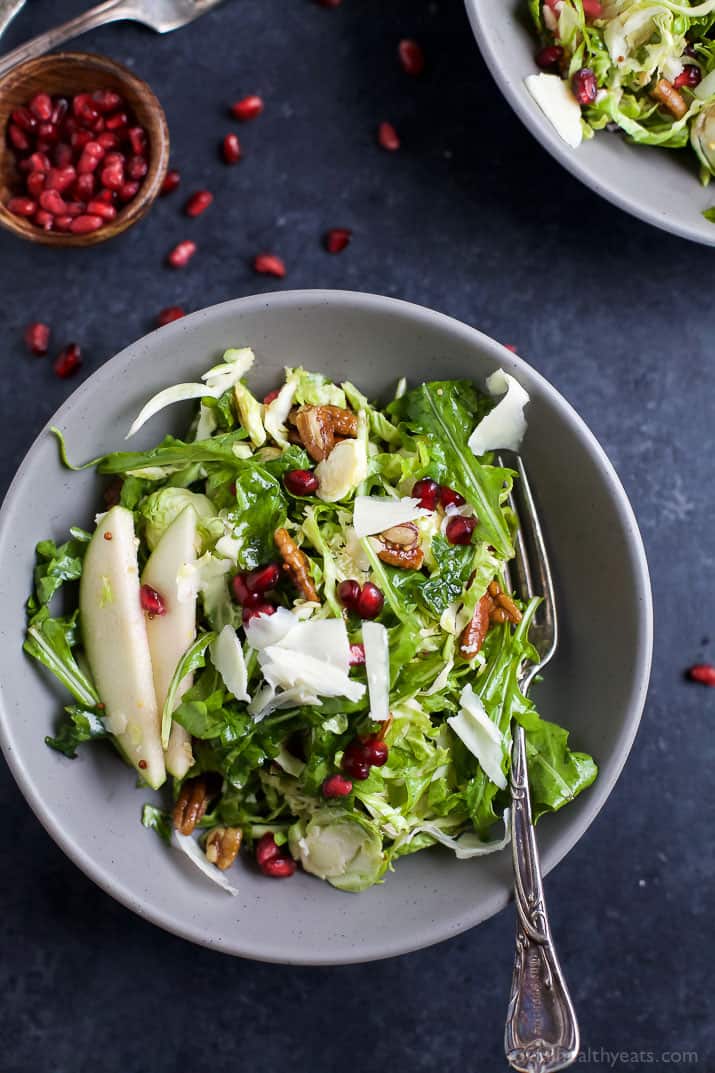 Shaved Brussel Sprout Salad filled with apples, pomegranate, candied pecans, and white cheddar cheese then tossed with a light Lemon Vinaigrette. This Brussel Sprout Salad is the perfect side dish for the holidays! | joyfulhealthyeats.com #glutenfree