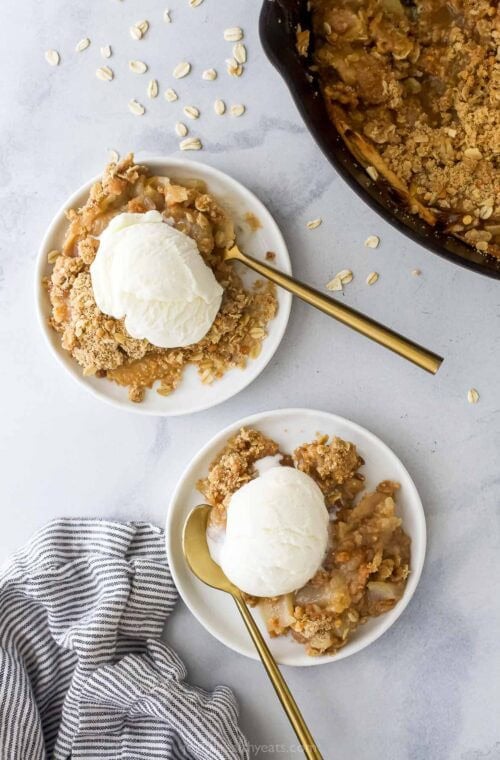 Two plates with apple pear crisp and vanilla ice cream.