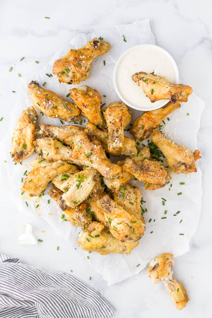overhead view of crispy baked garlic parmesan chicken wings with a cup of dipping sauce