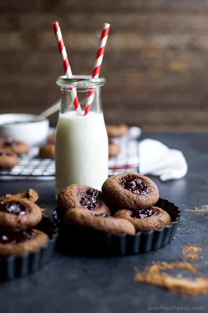 Chocolate Raspberry Thumbprint Cookies in mini tart pans next to a glass of milk