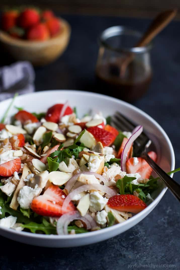 FARRO ARUGULA STRAWBERRY CHICKEN SALAD in a bowl topped with sliced almonds and goat cheese