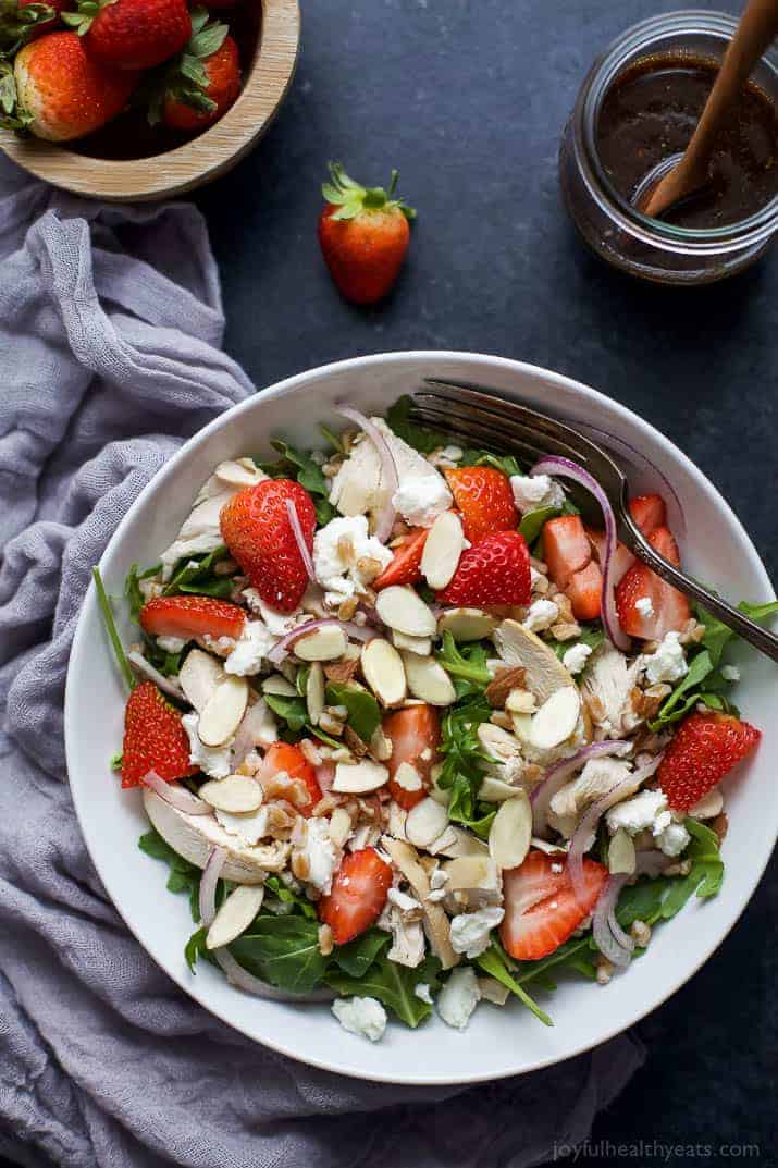 Top view of Farro Arugula Strawberry Chicken Salad with sliced almonds and goat cheese in a bowl