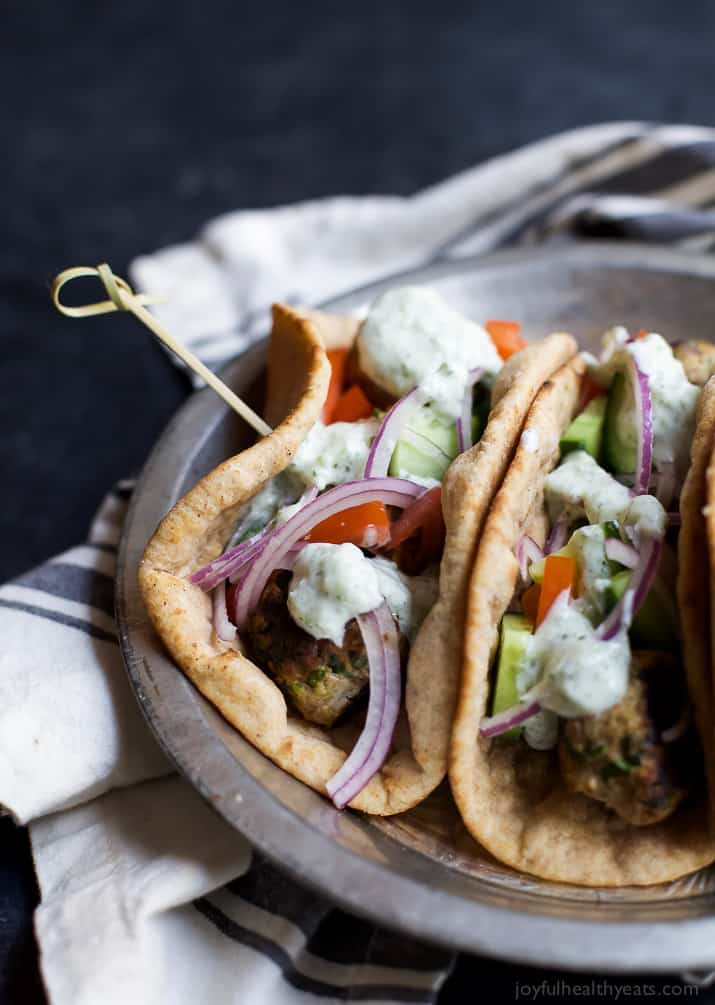 Two Greek Turkey Meatball Gyros topped with Tzatziki Sauce on a metal plate