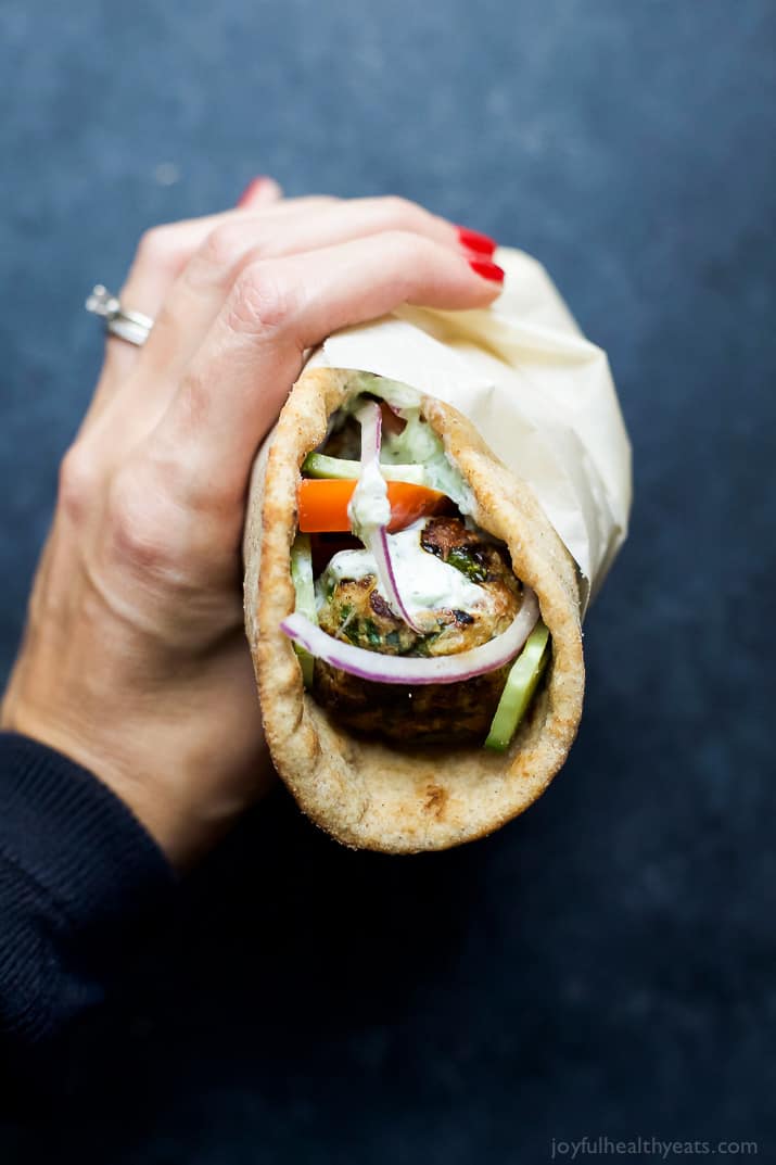 A hand holding a Greek Turkey Meatball Gyro