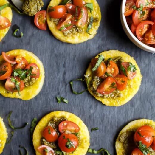 Five Pesto Polenta Bites with Tomato Bruschetta on a Gray Surface