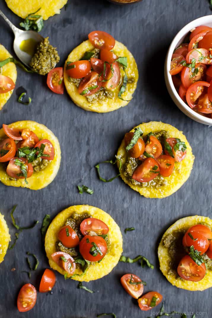 Five Pesto Polenta Bites with Tomato Bruschetta on a Gray Surface