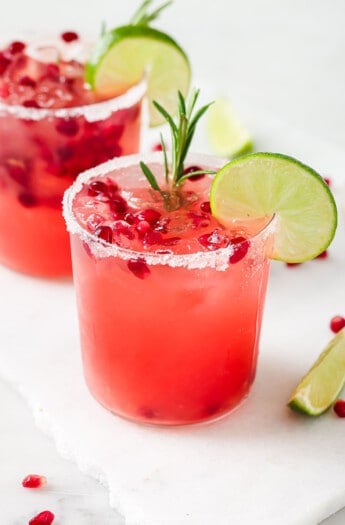 Pomegranate margarita with a rosemary sprig and lime wedge.