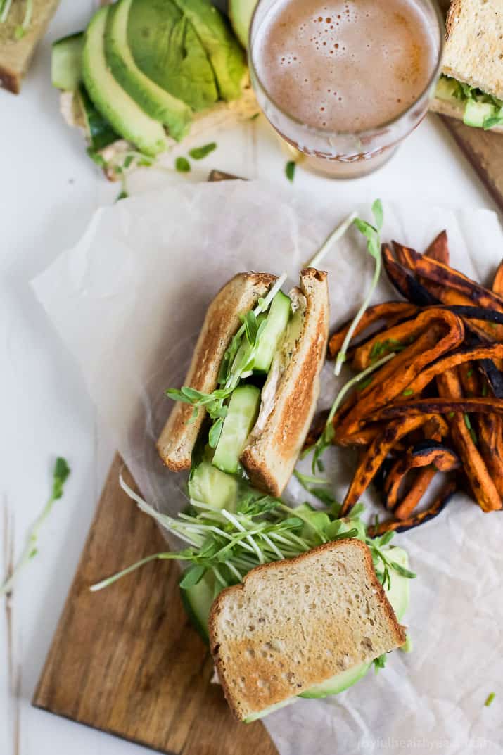 Top view of Cucumber Avocado Sandwich with sweet potato fries on parchment paper