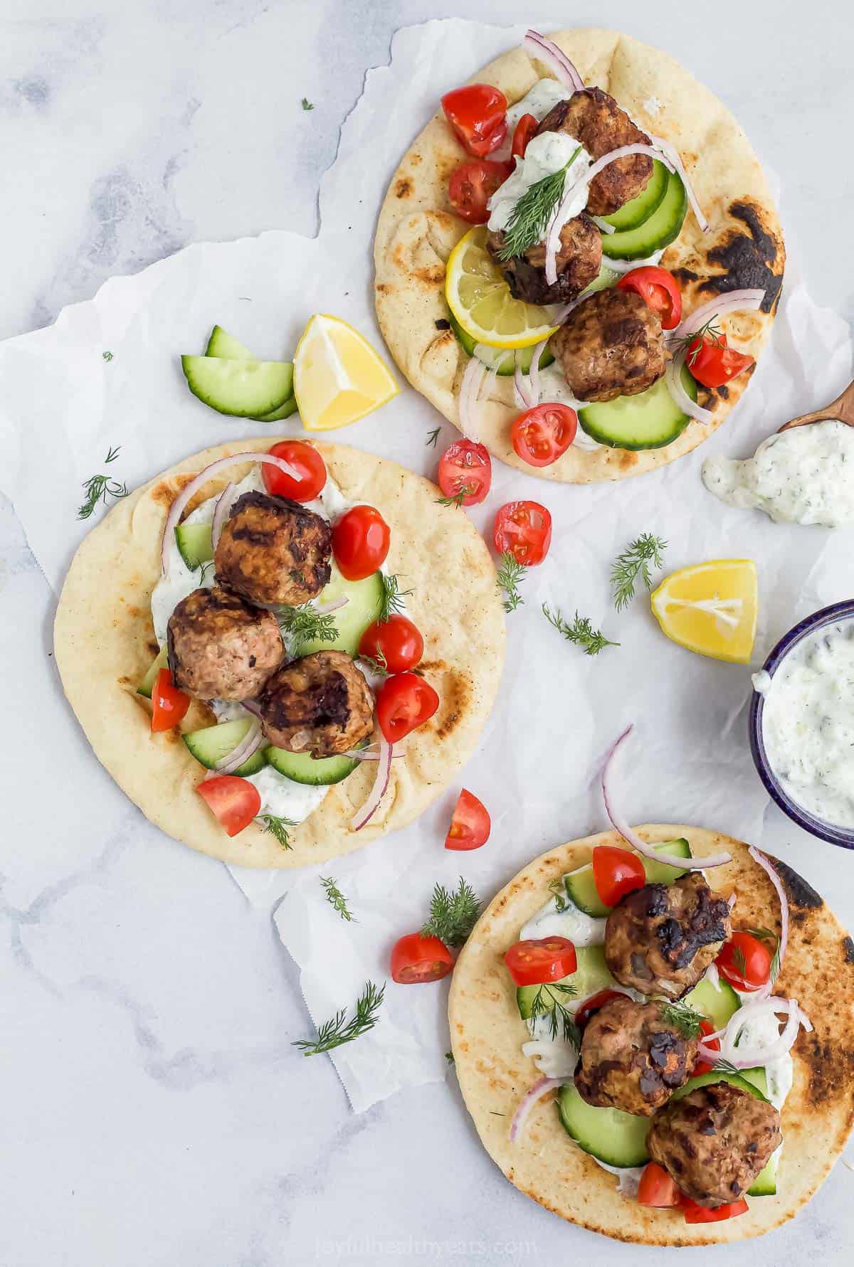 Overhead view of three turkey meatball gyros with tomato, cucumber, and tzatziki