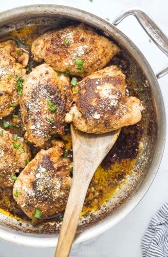 A chicken thigh on a wooden spoon.