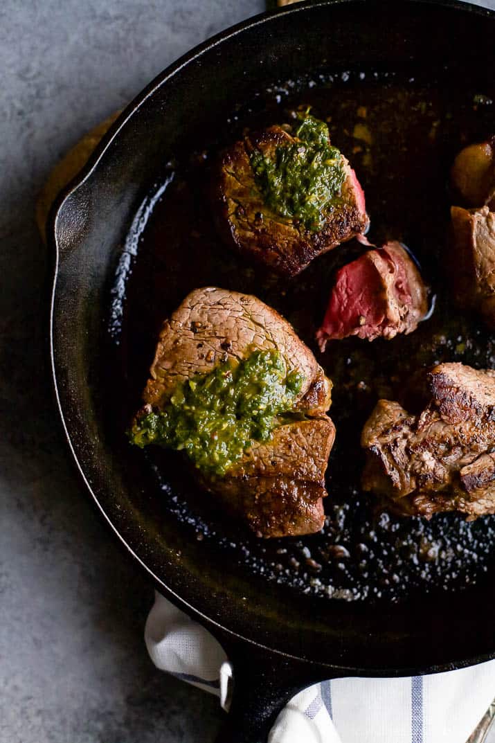 Top view of Filet Mignon in a cast iron skillet with chimichurri sauce