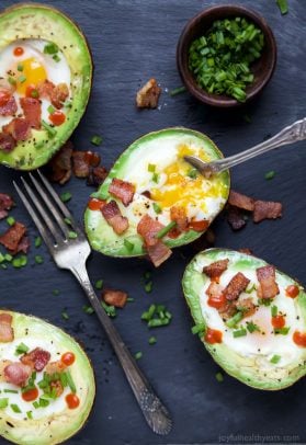 baked eggs in an avocado topped with crispy bacon