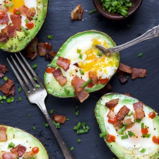 baked eggs in an avocado topped with crispy bacon