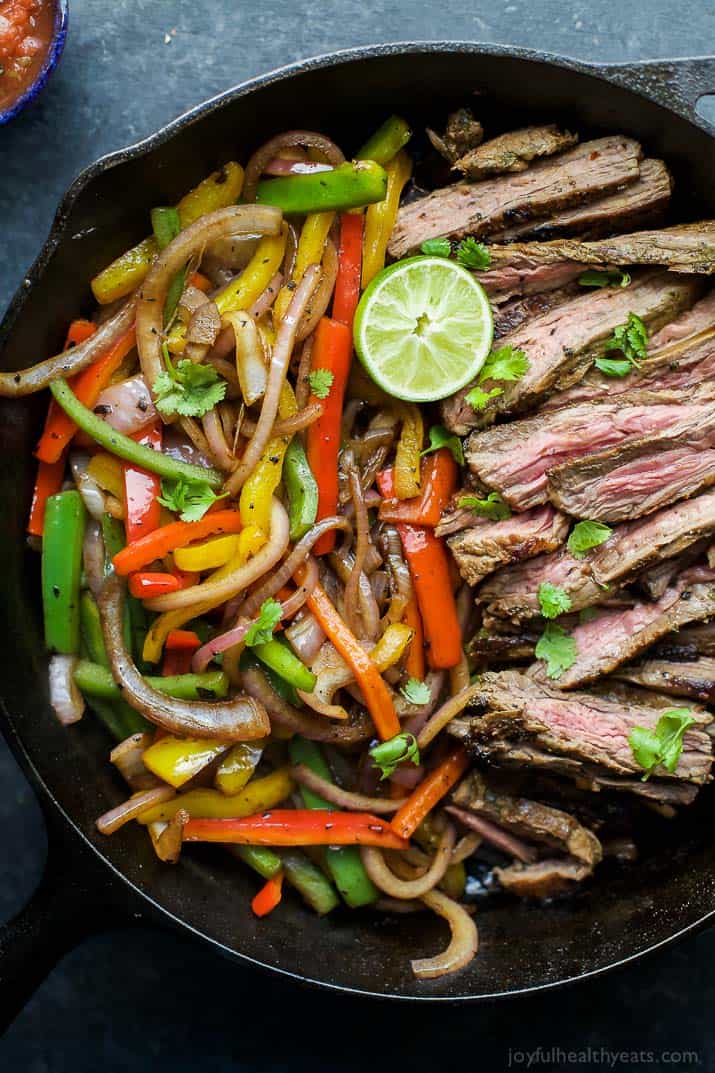 Homemade steak fajita burrito bowls filled with quinoa, fajita steak, avocado and a cilantro lime chimichurri sauce 