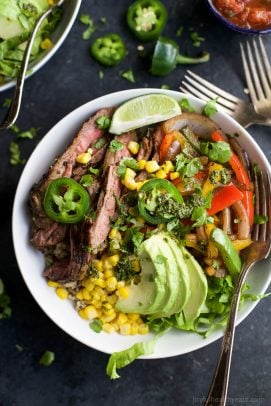 steak fajita burrito bowls in a bowl topped with avocado