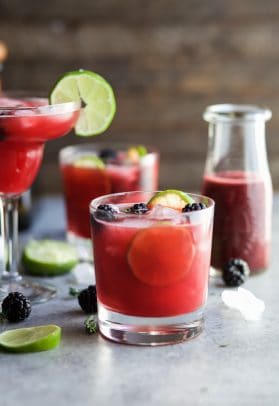 Thyme Blackberry Margaritas in different shaped glasses with limes and blackberries 