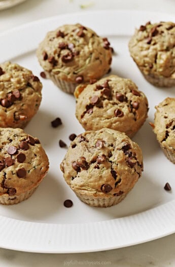 Freshly baked zucchini chocolate chip muffins on a serving plate.